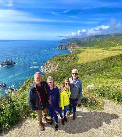 Group of travelers posing on a scenic Big Sur clif...