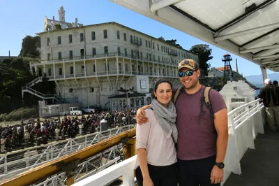 Couple on an Alcatraz ferry boat with the prison b...